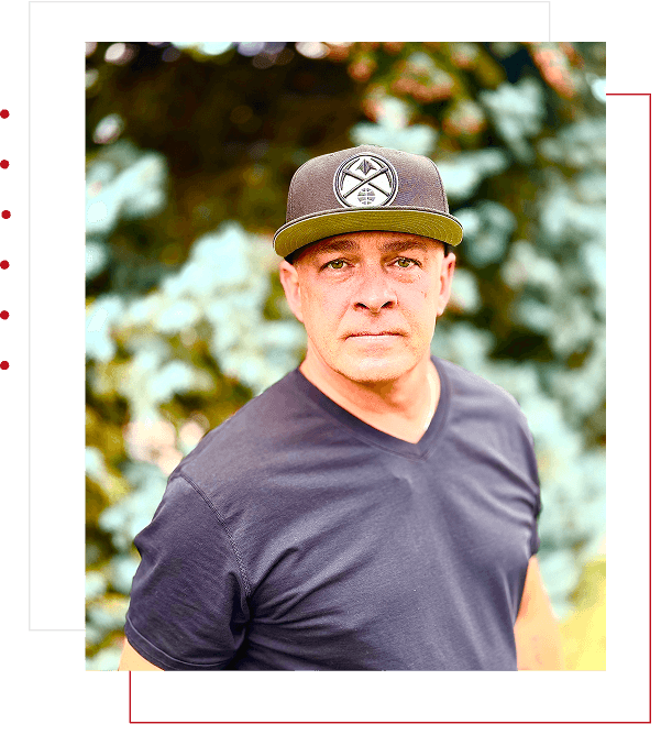 A man in a dark shirt and baseball cap outdoors.